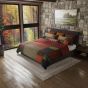 Image shows Woodland Square quilt on a bed in a cabin themed room with a stone wall and art over the bed.