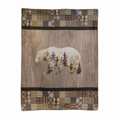 Chimera Bear Throw shows a bear silhouette with fall leaves on a wood pattern background with a plaid patchwork edge.  