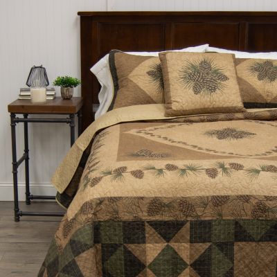 This quilt contains pine cones and branches surrounded by plaid patterns.
