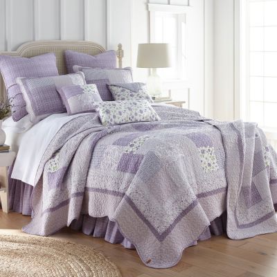 Quarter turn image of Lavender Rose on a bed in bedroom.