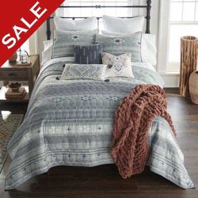this quilt features a striped Southwest pattern which is printed with a woven texture. Colors include smoky shades of slate grey and ivory
