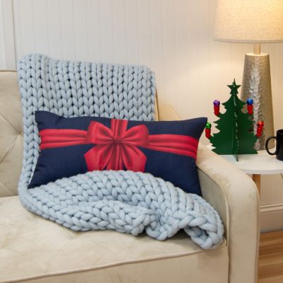 This rectangular pillow is blue and features a red ribbon tied in a bow.
