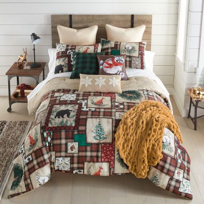 A comforter set from the Woodland Holiday collection, featuring rustic woodland motifs on a plaid background, perfect for creating a cozy and inviting atmosphere in your bedroom. Also shown coordinating decor pillows and chenille throw. Accessories sold s
