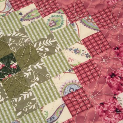 This quilt features small botanical and geometric prints are arranged in a classic Trip Around the World quilt pattern. Colors include watermelon, rose, deep mauve, olive green, tan, ivory, buttercream.  